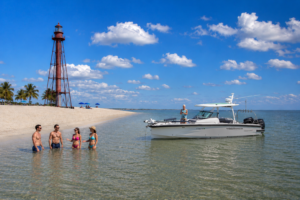 Florida Gulf Discovery Axopar 29 anchored near Sanibel Lighthouse Beach while guests enjoy the shallow Gulf waters on a sunny day in Southwest Florida.