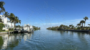 Private boat cruising through Boca Grande bayou canal lined with waterfront homes and palm trees in Southwest Florida