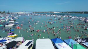 Large boating crowd gathering at Boca Grande sandbar in Southwest Florida with anchored boats, shallow turquoise water, and summer recreational activities