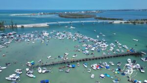 Aerial view of Boca Grande Sandbar in Gasparilla Pass with boats and people in shallow water during busy weekend with Florida Gulf Discovery