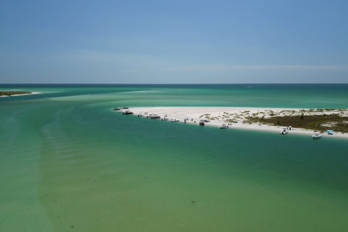 Aerial view of boats anchored along a white sandbar at Gasparilla Pass in Southwest Florida with turquoise Gulf waters