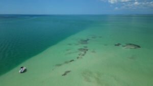 Drone view of shallow turquoise sandbar waters and small boat near Bokeelia in Pine Island Sound Florida