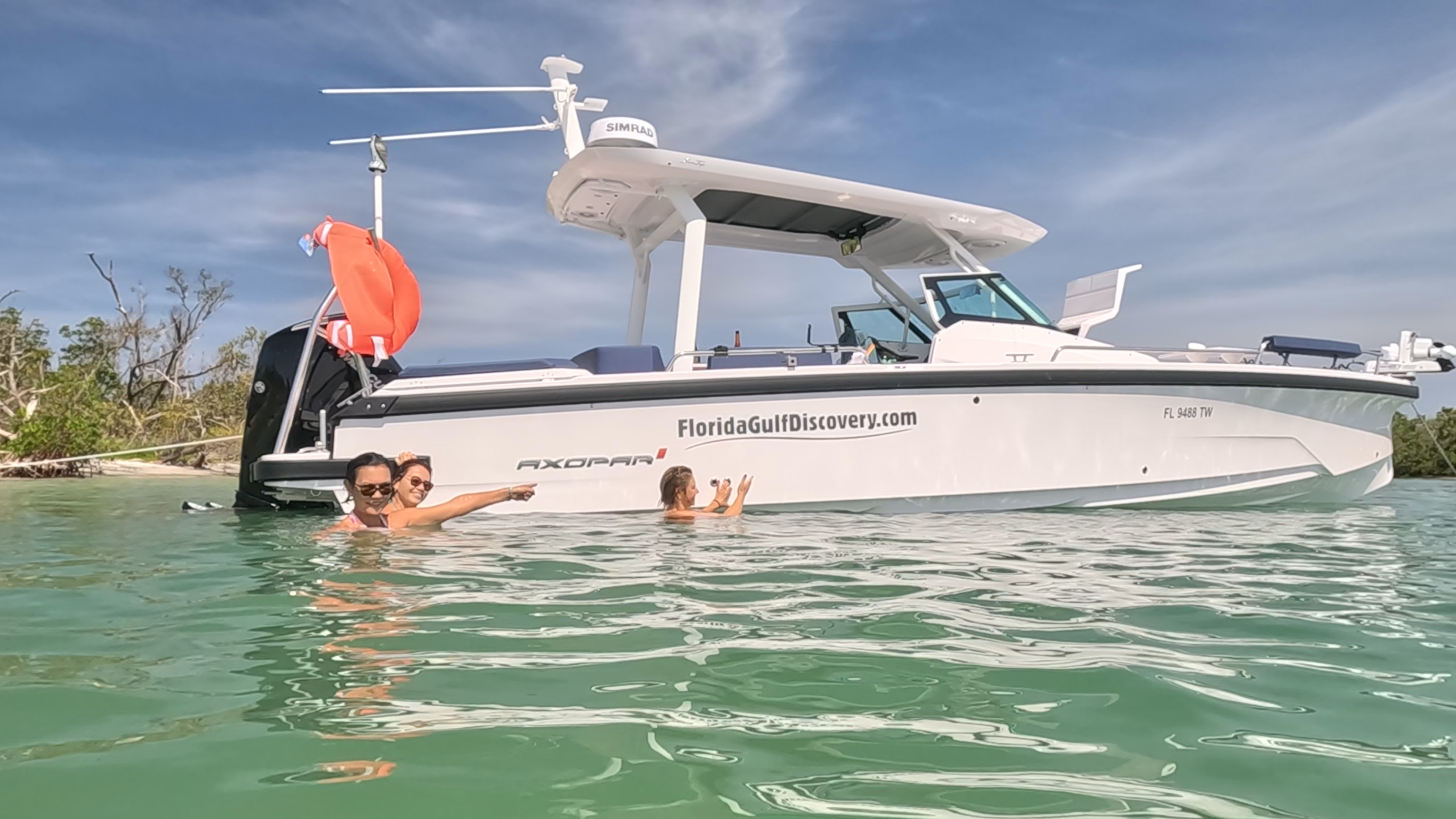 Guests swimming beside an Axopar 29 Sun Top during a private boat tour at Ski Alley near Stump Pass in Southwest Florida