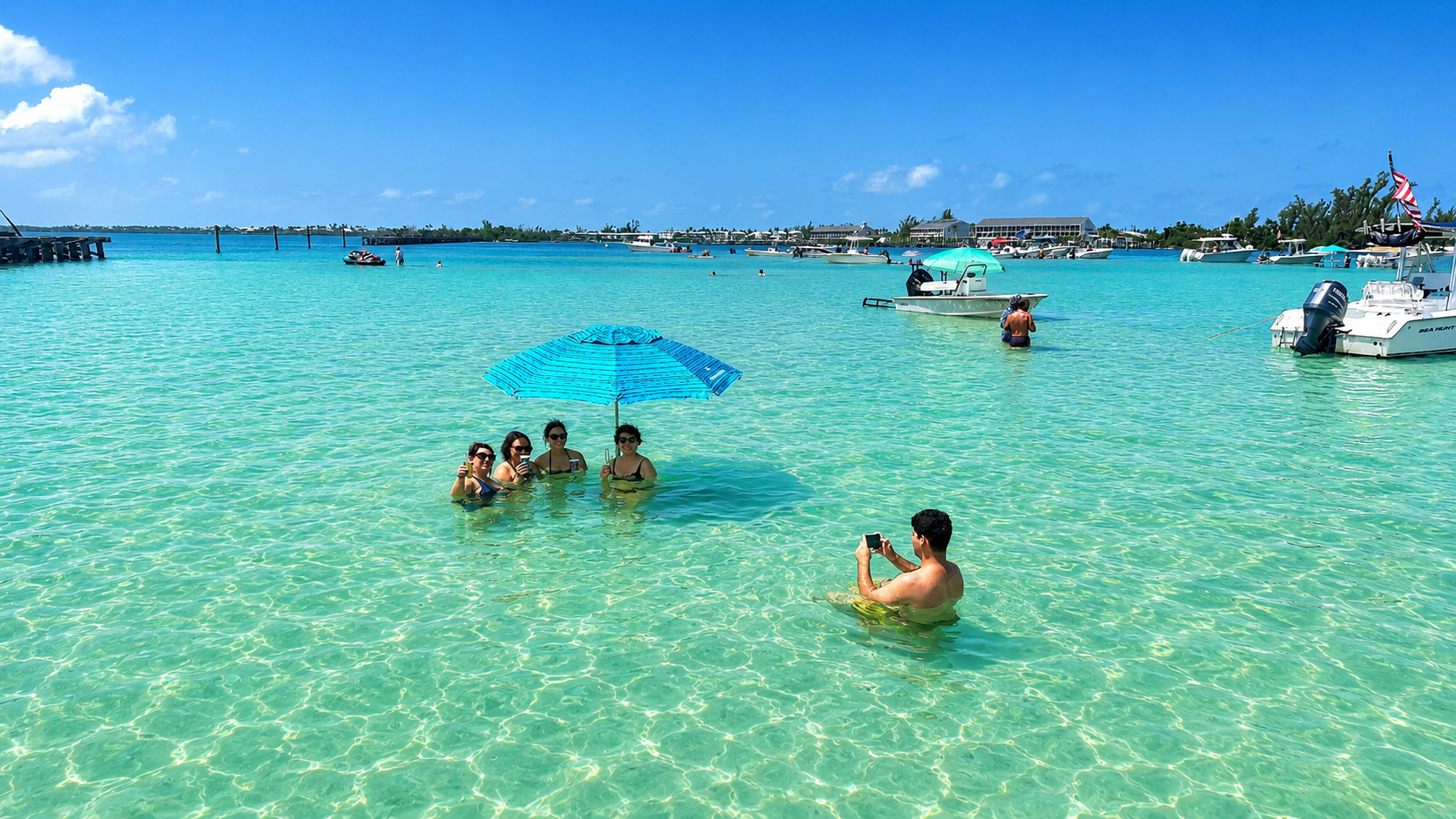 Family and friends relaxing in the crystal-clear waters of Boca Grande Sandbar in Southwest Florida under a beach umbrella.