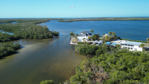 Drone view of Little Bokeelia Bay and Jug Creek on Pine Island, Florida, surrounded by mangrove forests and waterfront homes.