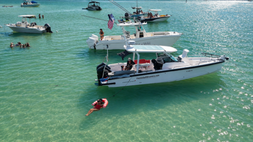 Florida Gulf Discovery Axopar 29 anchored at Boca Grande Sandbar while a guest relaxes in crystal-clear waters of Southwest Florida.