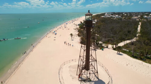 Drone view of the historic Sanibel Island Lighthouse overlooking the white-sand beach and Gulf waters in Southwest Florida.