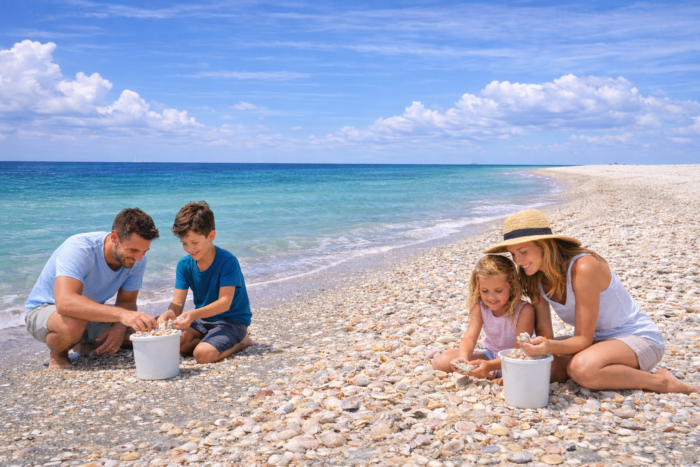 Family Shelling Boat Tour in Southwest Florida | Florida Gulf Discovery Family collecting seashells on a shell-covered beach during a private Shelling Boat Tour in Southwest Florida with Florida Gulf Discovery.