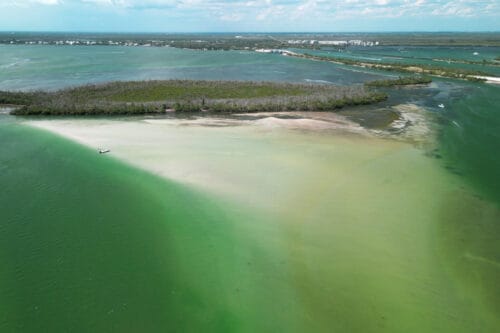 Aerial drone view of Bird Key and shallow sand flats in Gasparilla Sound near Placida, Florida, with a small boat illustrating the clear shallow water.