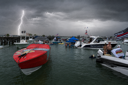 Storm clouds, lightning, and light rain over boats gathered at Boca Grande Sandbar during the Independence Day celebration on Florida's Gulf Coast.