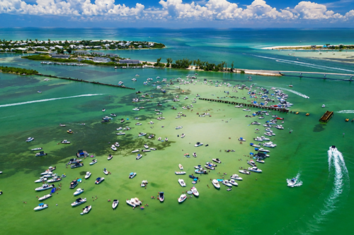 Drone view of Boca Grande Sandbar after a summer storm with turquoise water, anchored boats, and blue skies returning over Southwest Florida.