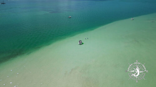 Drone view of Bokeelia Sandbar with shallow turquoise water and a boat anchored in Pine Island Sound, Florida.