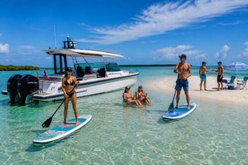 Luxury Axopar anchored at a Southwest Florida sandbar while guests paddleboard, relax in shallow water, and enjoy a private corporate boat charter.