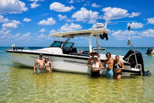 Guests enjoy a private boat tour while relaxing beside a modern Axopar boat anchored in the shallow waters of Padilla Beach on Cayo Costa, Florida.