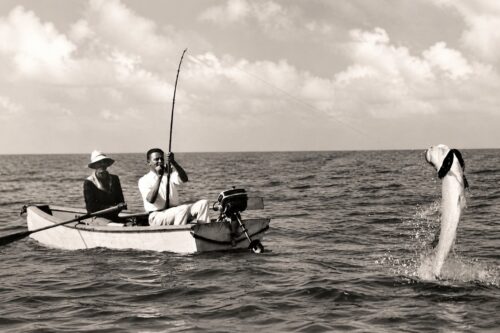 Historic black-and-white photograph of anglers fishing for tarpon from a small boat near Boca Grande Pass, Florida.