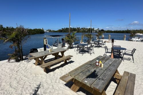 Outdoor waterfront seating at Jug Creek Marina Tiki Bar overlooking Jug Creek in Bokeelia, Florida.