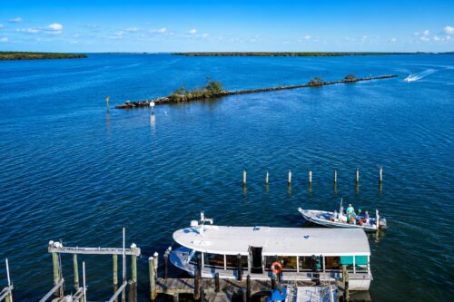 Drone view of Wilson Cut at Pineland on Pine Island Sound, Florida, showing the navigation channel, breakwater, marina docks, and recreational boats.