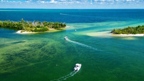 Aerial drone view of Shell Pass in Pine Island Sound near Bokeelia, Florida, with boats navigating between mangrove islands and shallow turquoise waters.