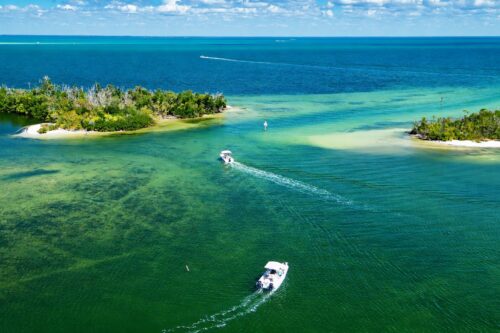 Aerial drone view of Shell Pass in Pine Island Sound near Bokeelia, Florida, with boats navigating between mangrove islands and shallow turquoise waters.