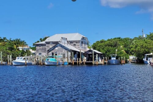 Historic Whidden's Marina in Boca Grande, Florida, viewed from the water, featuring its iconic Old Florida wooden buildings and marina docks.