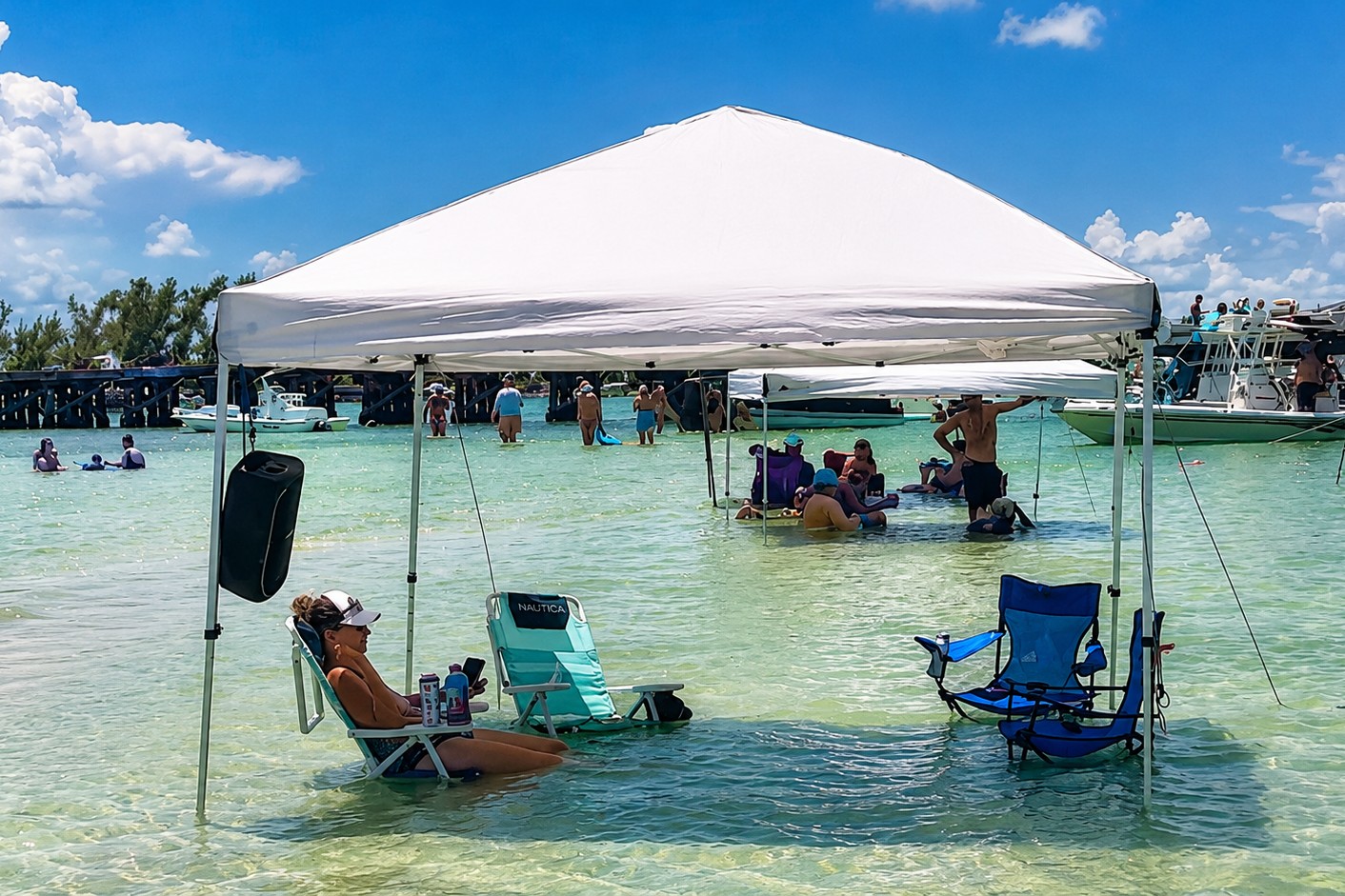 Guests relaxing beneath a beach canopy in the shallow turquoise waters of Boca Grande Sandbar, Southwest Florida.