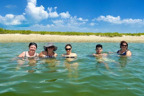 Guests swimming in the calm emerald-green waters of Cayo Costa Lagoon during a private boat tour in Southwest Florida.